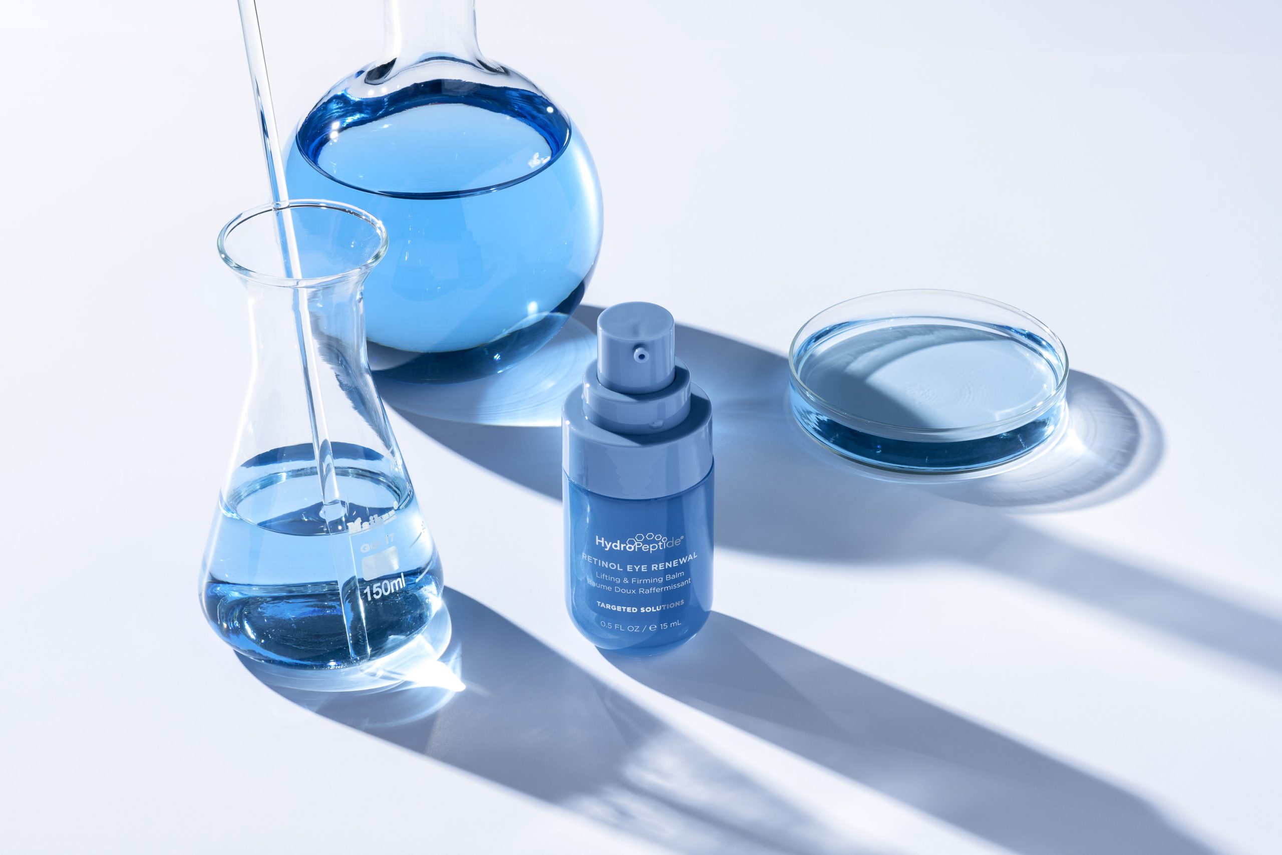 HydroPeptide eye balm with blue lab flasks.