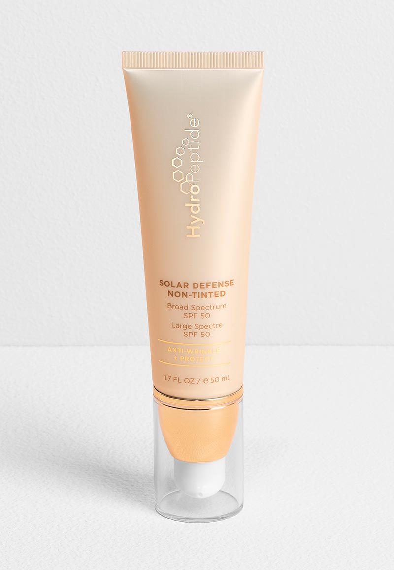 HydroPeptide Solar Defense Non-Tinted Broad Spectrum SPF 50 anti-wrinkle and protect sunscreen in a gold and white pump tube (1.7 FL OZ / e 50 mL).