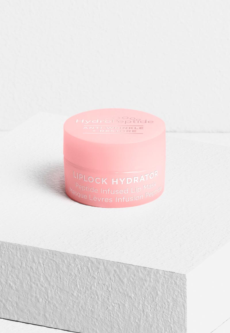 A small light pink jar of HydroPeptide Liplock Hydrator Peptide Infused Lip Mask resting on a textured white block against a white background.