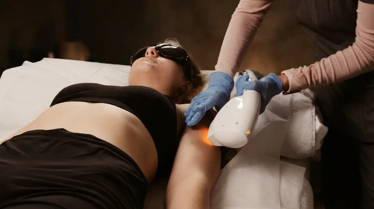 Technician performing laser hair removal treatment on a woman's underarm.